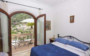 a bedroom with a bed and a balcony with a table at Villa Palumbo in Positano