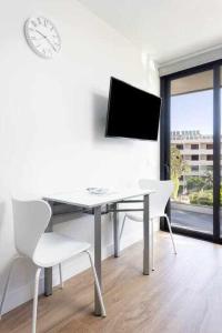 a white office with a desk and a clock on a wall at Sunnyland Lago Martianez 3 in Puerto de la Cruz