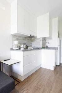 a white kitchen with white cabinets and a table at Sunnyland Lago Martianez 3 in Puerto de la Cruz