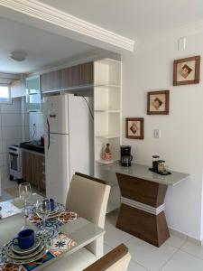 uma cozinha com uma mesa e um frigorífico branco em Jóia Rara pertinho da Praia! em João Pessoa
