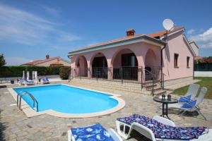 una piscina di fronte a una casa rosa di Villa Nel Rosa a Poreč (Parenzo)