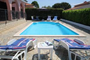una piscina con due sedie a sdraio e un tavolo e due sedie a sdraio di Villa Nel Rosa a Poreč (Parenzo)