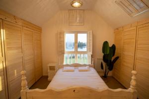 a bedroom with a bed with white sheets and a window at Stunning lodge on the lake in South Cerney