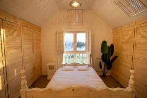 a bedroom with a bed with white sheets and a window at Barefoot lodge in South Cerney