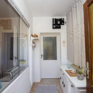 ein Bad mit einem Waschbecken und eine Tür mit einem Fenster in der Unterkunft Beach House Wild Paradise in Silba