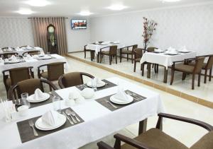 a dining room with white tables and chairs at Hotel Vardonze in Bukhara