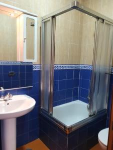 y baño de azulejos azules con ducha y lavamanos. en Hostal Zamorán en Madrid