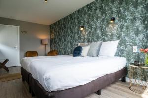 - une chambre avec un grand lit et un mur vert dans l'établissement Hotel het Anker van Texel, à De Cocksdorp
