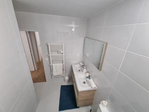 a white bathroom with a sink and a mirror at Maison Chaleureuse in Villepinte