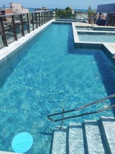 een zwembad met blauw water in een gebouw bij Flat Porto Blue 104 Centro Porto de Galinhas in Porto De Galinhas