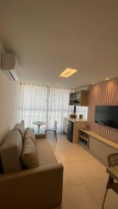 a living room with a couch and a flat screen tv at Flat Porto Blue 104 - Centro Porto de Galinhas in Porto De Galinhas