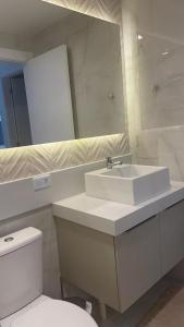een badkamer met een wastafel, een toilet en een spiegel bij Flat Porto Blue 104 Centro Porto de Galinhas in Porto De Galinhas