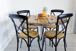 una mesa de madera con 4 sillas y un bol de fruta en L'Eden Blue à Saint Gilles les Bains, magnifique vue mer en Saint-Gilles-les-Bains
