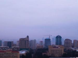 a city skyline with skyscrapers on a foggy day at Explore Baku from YSB Apartment in Baku