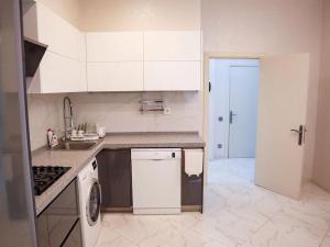 a kitchen with white cabinets and a sink and a dishwasher at Explore Baku from YSB Apartment in Baku