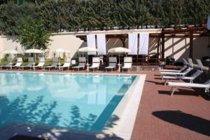 uma piscina com espreguiçadeiras e guarda-sóis em Salerno Mare e Luci Village Palinuro em Palinuro