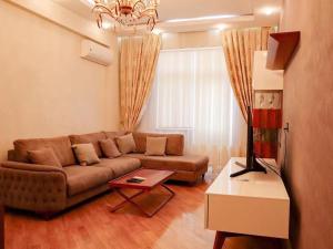 a living room with a brown couch and a table at Explore Baku from YSB Apartment in Baku