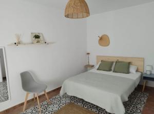 a white bedroom with a bed and a chair at Casa Rural Berta in El Picazo