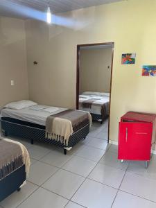 - 2 lits dans une chambre avec un miroir et une commode rouge dans l'établissement Barra Adventure Pousada, à Mataraca