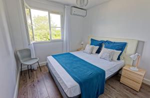 1 dormitorio con cama con sábanas azules y ventana en L'Eden Blue à Saint Gilles les Bains, magnifique vue mer, en Saint-Gilles-les-Bains