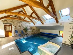 a swimming pool in a house with a ceiling with windows at Ysgubor Isaf in Llanglydwen