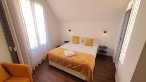 ein weißes Schlafzimmer mit einem Bett und einem Stuhl in der Unterkunft Seasons Porto-Gaia by MyStay in Vila Nova de Gaia