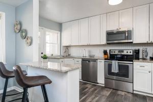 una cocina con armarios blancos y electrodomésticos de acero inoxidable en Recently renovated 3BR home near Heritage Park! en Dundalk