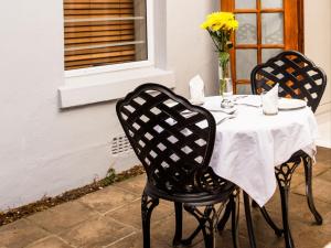 a table with a white table cloth and two chairs at The Marilyn on Sea Point in Cape Town