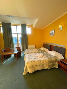 ein Hotelzimmer mit 2 Betten und einem Stuhl in der Unterkunft Hotel SenS in Mierzyn