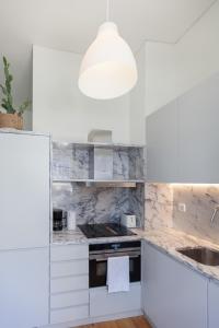 cocina blanca con encimeras de mármol y lámpara en FLH Downtown Modern Art Flat, en Lisboa
