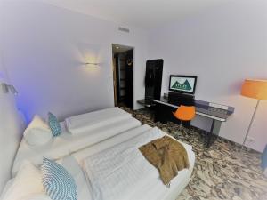 a bedroom with two beds and a desk and a television at Styles Hotel München Messe in Munich