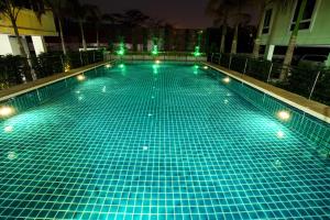 una gran piscina con luces verdes. en Patt Serviced Apartments en Chon Buri