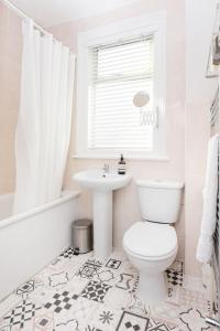 La salle de bains blanche est pourvue de toilettes et d'un lavabo. dans l'établissement Newly renovated large 4/5 bedroom Victorian terrace house with garden., à Londres