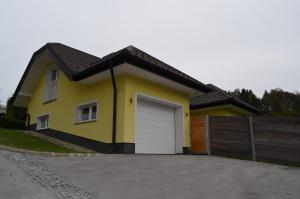 una casa amarilla con garaje blanco en Hiška pod gradom en Celje