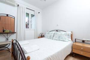 a white bedroom with a bed and a window at Coral Cottage House by A&D Properties in Porto Rafti