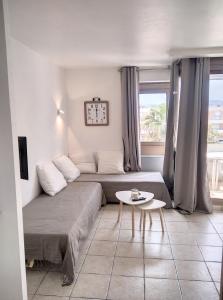 1 dormitorio con cama, mesa y reloj en Résidence Graziella Studio 502, en Juan-les-Pins