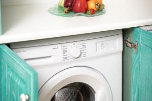 a washing machine under a counter with a plate of fruit at Coral Cottage House by A&D Properties in Porto Rafti