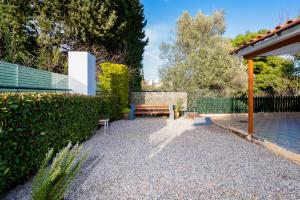 a bench sitting next to a hedge and a fence at Coral Cottage House by A&D Properties in Porto Rafti