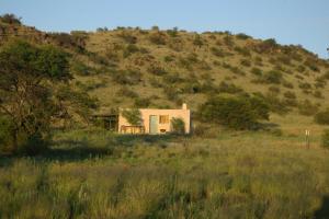 una pequeña casa en una colina en un campo en Karoo Pred-a-tours/Cat Conservation Trust en Cradock