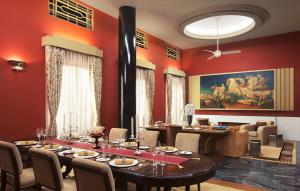 a dining room with red walls and a table and chairs at Umaid Bhawan Palace Jodhpur in Jodhpur