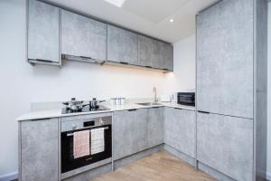 a kitchen with stainless steel appliances and gray cabinets at Cresta House - Modern Apartments in Luton