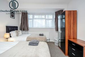 - une chambre avec 2 lits et une commode dans l'établissement Dwellers Delight Living Ltd Serviced Accommodation Fabulous House 3 Bedroom, Hainault Prime Location ,Greater London with Parking & Wifi, 2 bathroom, Garden, à Chigwell