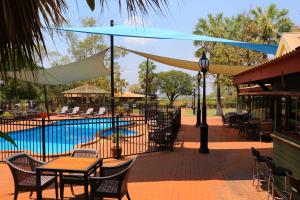 a patio area with tables, chairs and umbrellas at Kimberley Hotel in Halls Creek