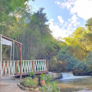 a wooden bridge over a river with a waterfall at Pousada do Coura in Pouso Alto