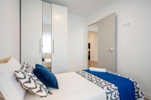 1 dormitorio con cama blanca y almohadas azules en For You Rentals Cozy Apartment La Vaguada Madrid PMO10 en Madrid