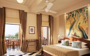 a bedroom with a bed with a painting on the wall at Umaid Bhawan Palace Jodhpur in Jodhpur