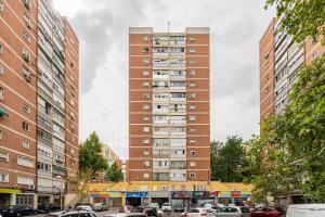 ein hohes Gebäude mit Autos auf einem Parkplatz in der Unterkunft For You Rentals Cozy Apartment La Vaguada Madrid PMO10 in Madrid