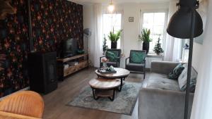 een woonkamer met een bank en een tafel bij Groot familiehuis voor 6 personen in landelijke, rustige omgeving in Breezand