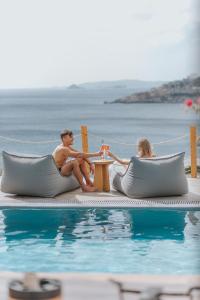 a man and a woman sitting next to a swimming pool at myMykonos Villa I in Platis Gialos