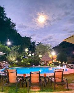 a group of chairs and a pool at night at Pousada do Coura in Pouso Alto